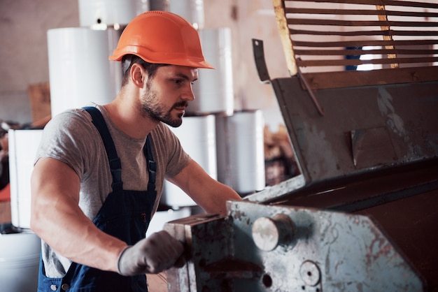 portrait of a young worker in a hard hat at a large waste recycling factory.