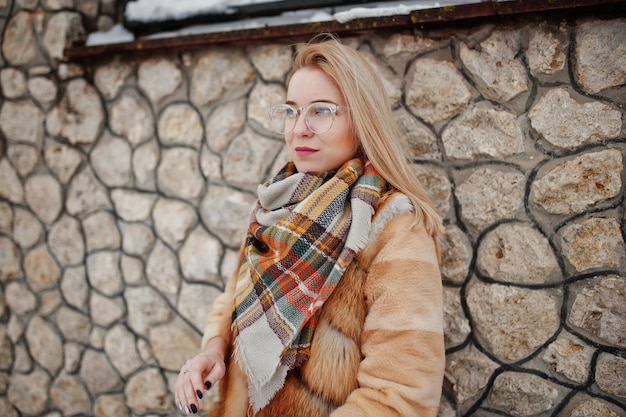 Free photo portraiy of blonde girl in glasses red fur coat and scarf at winter day