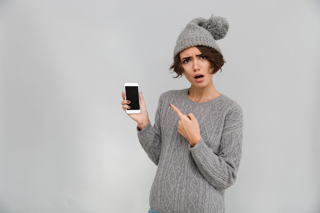 Porttrait of confused young woman in sweater and hat