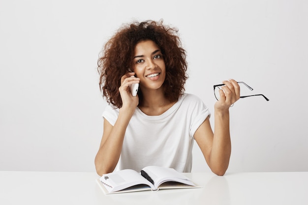 Posh young african girl taking a break from her study, talking to mother on phone, discussing new boyfriend or a call from future employer she's hired for first job, given an assignment marketing.