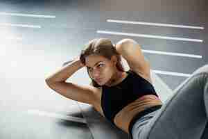 Бесплатное фото Шикарная молодая женщина делает скручивания пресса, чтобы подготовить свое тело к лету. концепция фитнеса.
