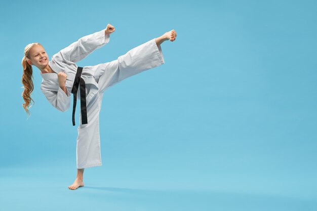 Positiive karate girl practicing kick foot forward.