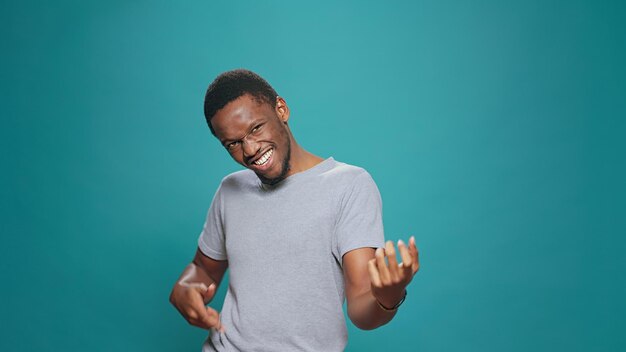 Positive adult doing air guitar performance in front of camera, playing modern instrument to have fun in studio. Carefree happy man having musical skills, singing and dancing for leisure activity.