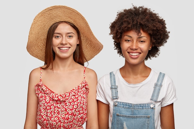 Positive Afro American girl has toothy smile, shows white teeth, wears dungarees