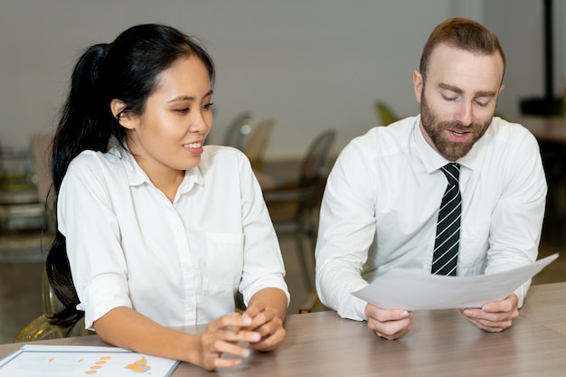 Positive bearded boss and assistant discussing papers