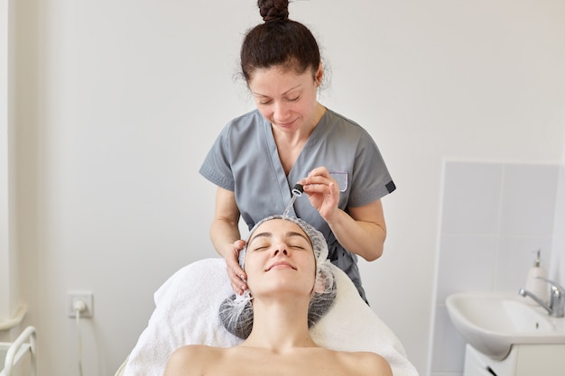 Positive beautician works at beauty parlor.