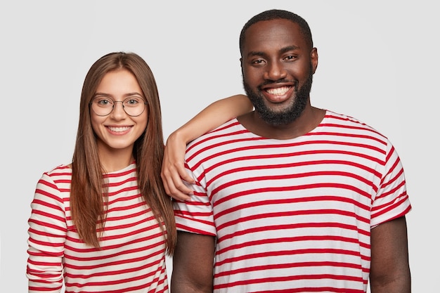 Positive best friends posing against the white wall