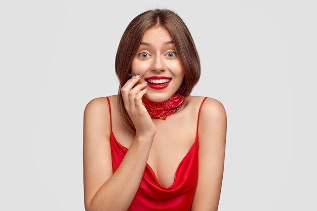 positive brunette young woman posing against the white wall