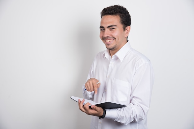 Positive businessman holding notebook on white background.