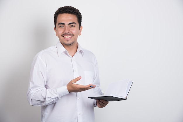 Positive businessman with notebook laughing on white background.