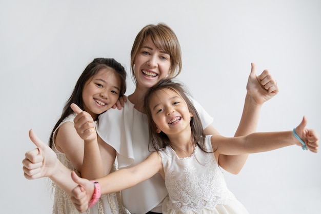 Positive caucasian mother and daughters showing thumbs up