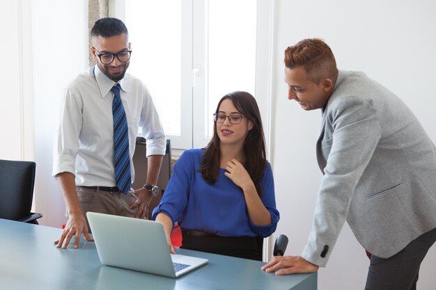 Positive colleagues analyzing report on laptop