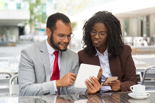 Free photo positive colleagues comparing data on their gadgets