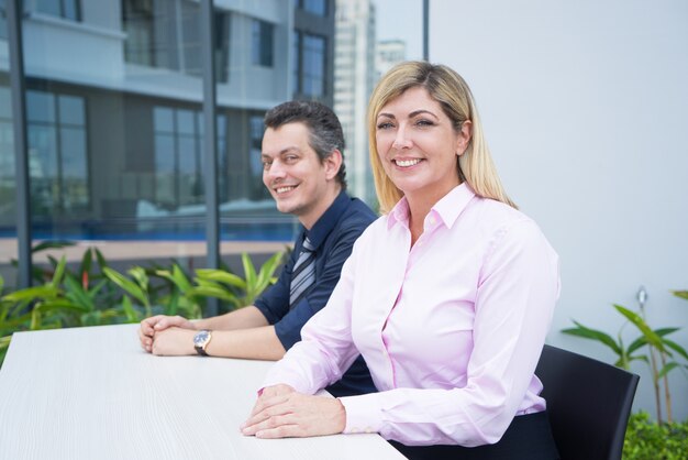 Positive confident attractive businesswoman and her assistant sitting at table
