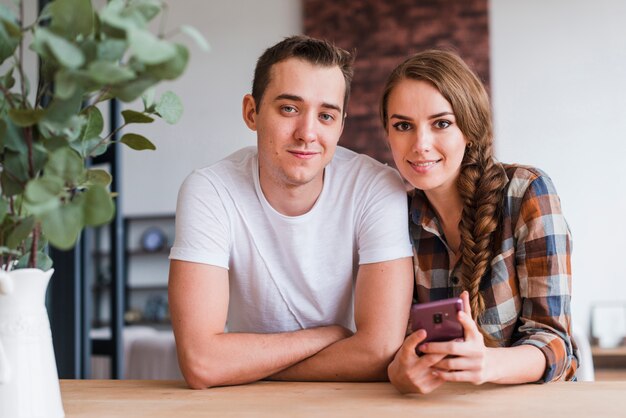 Позитивные пара с смартфон возле стола у себя дома