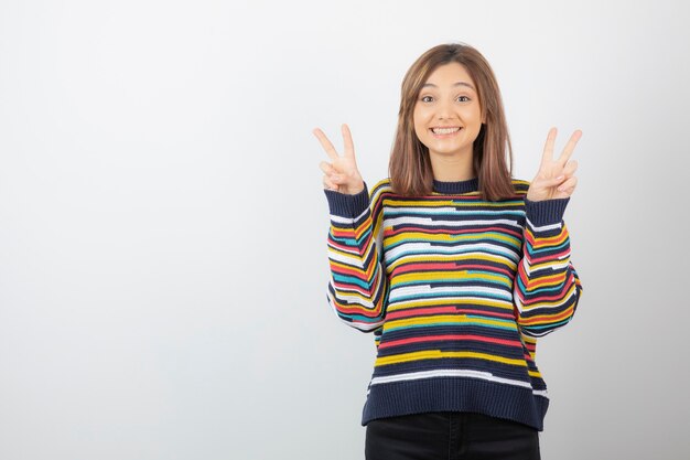 positive cute woman model standing and showing victory sign.