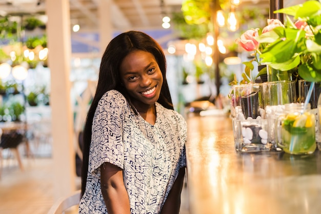 Позитивная темнокожая женщина смешанной расы радуется хорошему отдыху в кафе