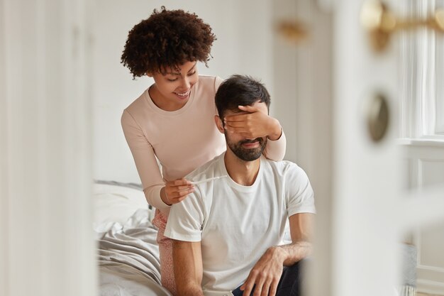 긍정적 인 어두운 피부를 가진 여자가 남편의 눈을가립니다.