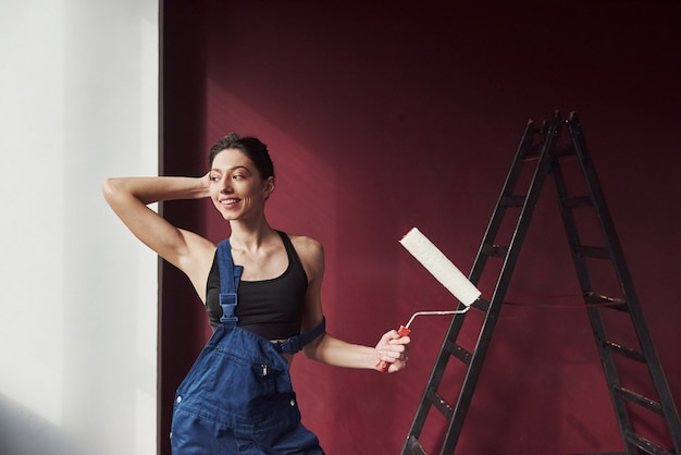 Positive emotions. Young housewife decided to glue wallpaper in her new house in the room