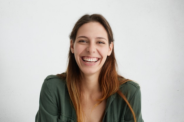 Positive European woman with long hair being glad, smiling pleasantly