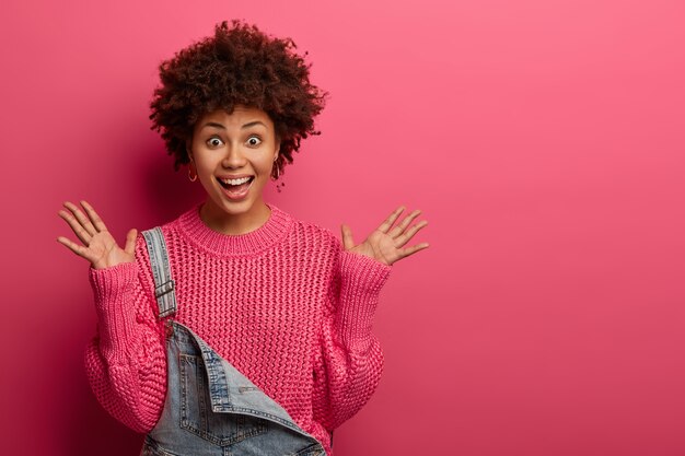 Positive excited Afro American woman raises palms with joy