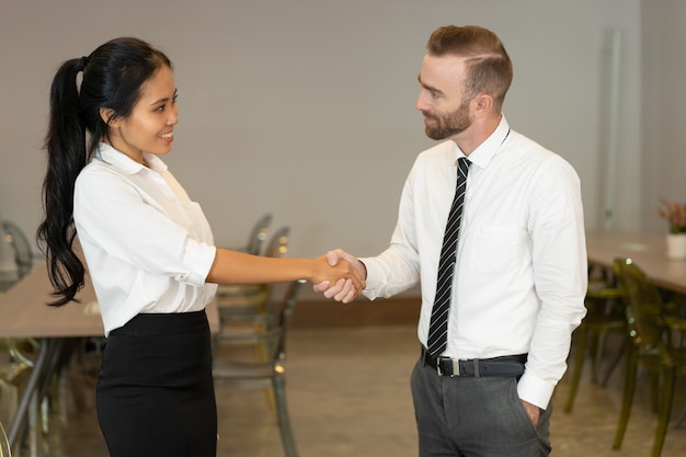 Positive executives greeting each other and making handshake