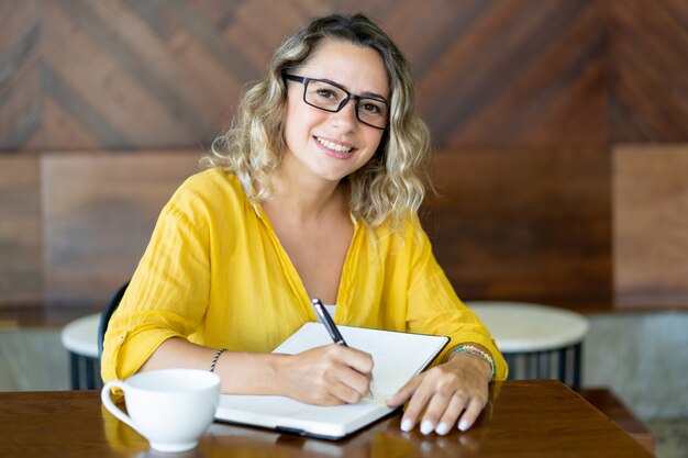 숙제를 하 고 안경에 긍정적 인 여성 학생