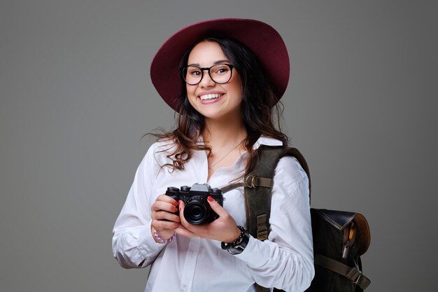 Positive female tourist with photo camera and travel backpack.