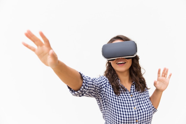 Utente femminile positivo negli occhiali di protezione di vr che tocca aria e sorridere