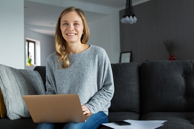 彼女のリビングルームでポーズをとって肯定的なフリーランスの労働者