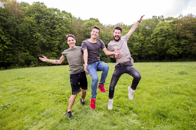 Free photo positive friends jumping on meadow