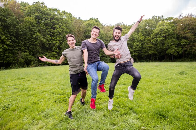 Positive friends jumping on meadow