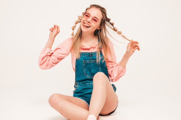 Positive and funny model sitting on grey wall in studio