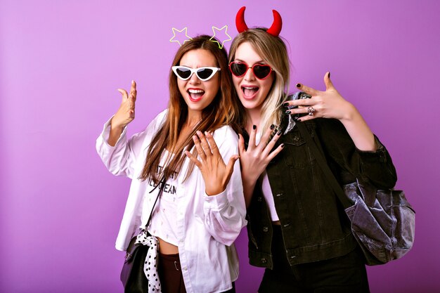 Positive funny portrait of the pretty American women enjoy their party, youth hipster clothes, crazy carefree easy going mood, two best friends girls.