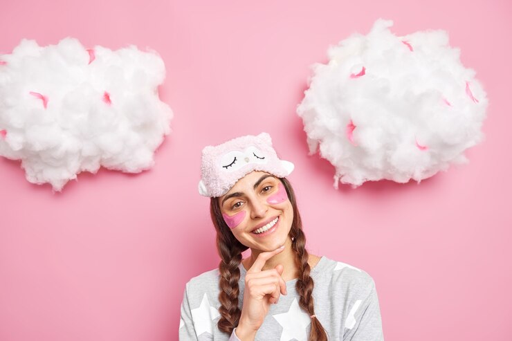 Free Photo positive gentle caucasian female model has two pigtails smiles broadly tilts head wears blindfold and pajama