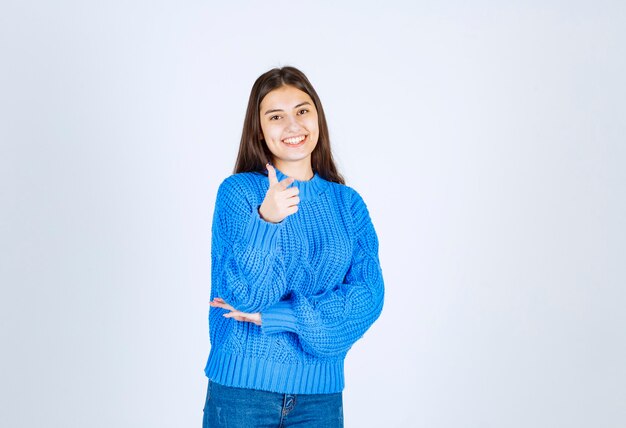 positive girl in sweater pointing on white.