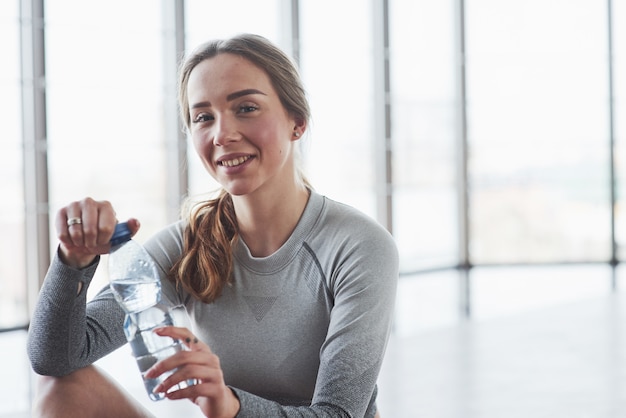 Foto gratuita ragazza positiva che prende una pausa. la giovane donna allegra ha una giornata di fitness in palestra al mattino