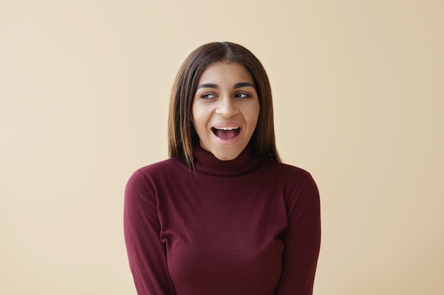 Positive human emotions and feelings. picture of emotional young mixed race lady looking sideways with excited expression, opening mouth widely