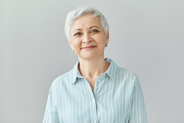 Positive human reactions, feelings and emotions. Charming elegant middle aged sixty year old female with short gray hair  with pleased smile, her eyes full of happiness and joy