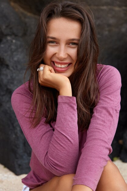 Positive joyful woman with glad facial expression, dressed in casual sweater, smiles positively 