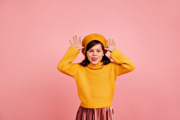 Positive kid making funny faces.  caucasian child posing on pastel wall.