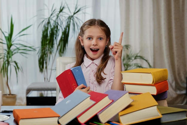 Позитивная маленькая девочка любит читать много книг.