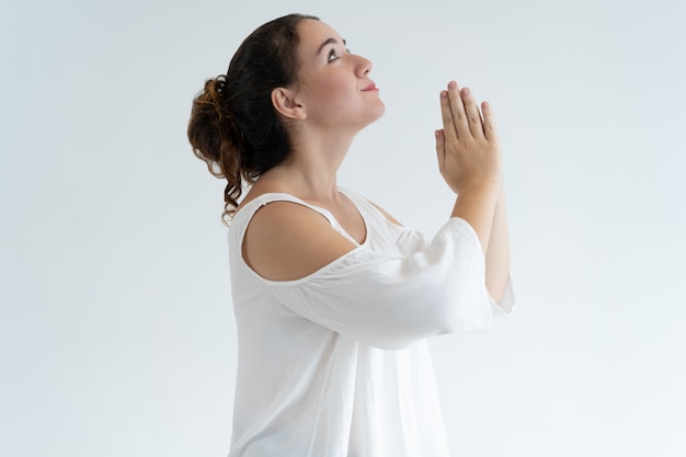 Positive lovely woman holding hands together and praying