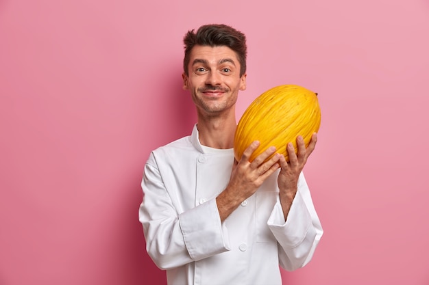 Positive male chef holds big ripe yellow melon