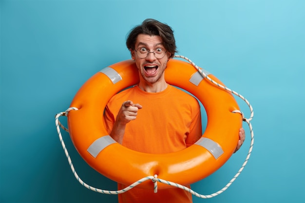 Бесплатное фото Позитивный мужчина-турист позирует с надутым кольцом для плавания, учится плавать прямо на камеру