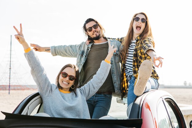 Positive man and crying women having fun and leaning out from auto