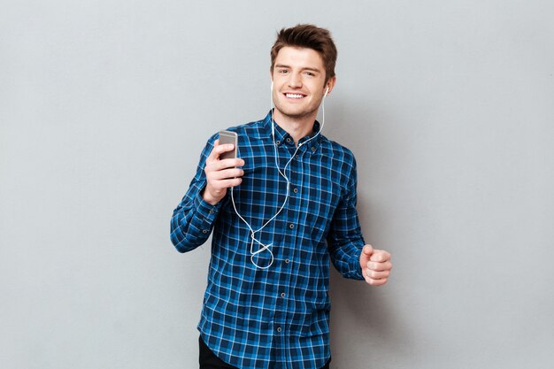 Positive man dancing while listening music on smartphone