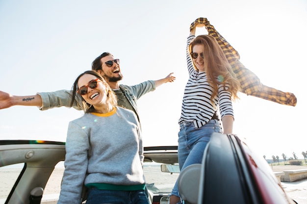 Positive man and smiling women with skirt in hand having fun and leaning out from car