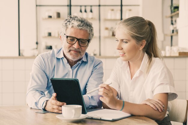 Positive mature male mentor explaining work details to intern.