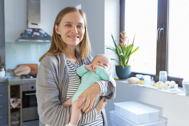 Positive new mother rocking cheerful baby